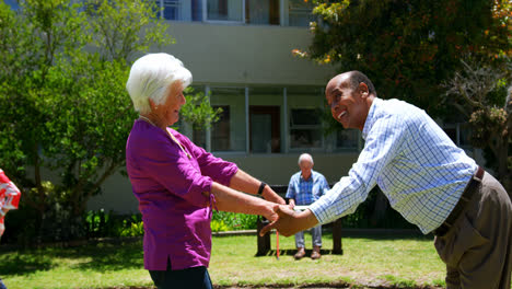 Vista-Lateral-De-Una-Pareja-Activa-De-Raza-Mixta-Bailando-Juntos-En-El-Jardín-De-Una-Residencia-De-Ancianos-4k