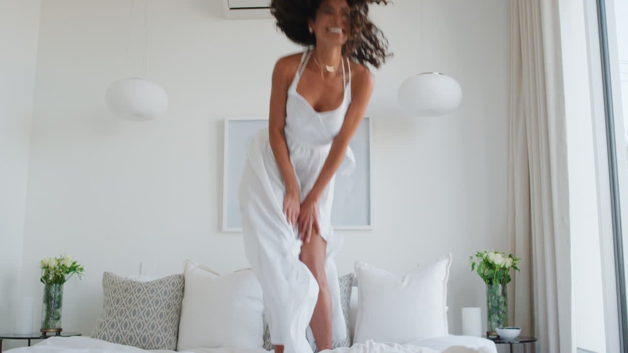 donna felice che salta sul letto divertendosi ridendo godendosi uno stile di vita indipendente celebrando la libertà