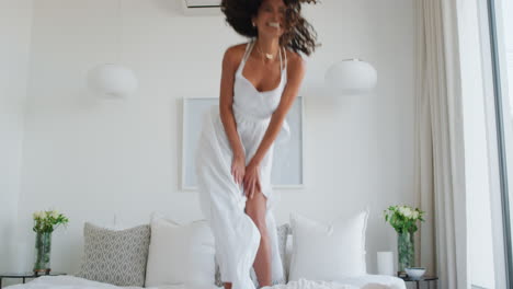 mujer feliz saltando en la cama divirtiéndose riendo disfrutando de un estilo de vida independiente celebrando la libertad