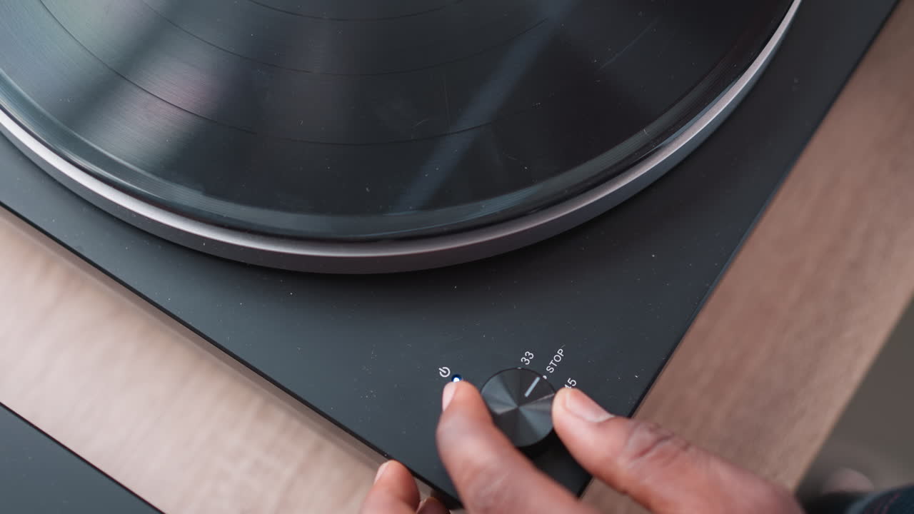 Hand of man turning on switch on turntable. African American music enthusiast spends weekend indulging in favorite tunes through vintage turntable. Evening leisure