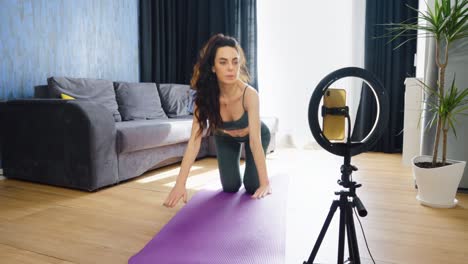 mujer grabando video haciendo ejercicio de gato y vaca