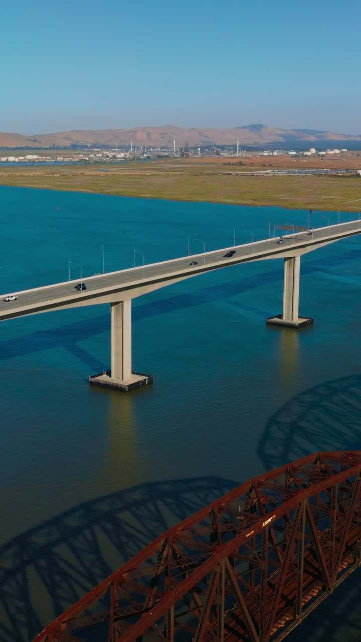 Three neighboring bridges over blue calm water of Carquinez Strait. Martinez-Benicia bridges with lots of cars on. Sunny clear day footage. Vertical video