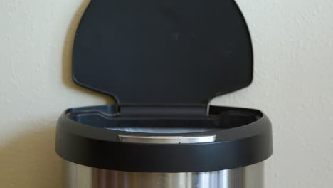 man throws away banana peel in motion sensing touchless trash can - close-up