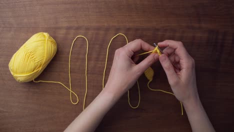 Top-shot-of-a-piece-of-yellow-wool-laying-on-a-wooden-table