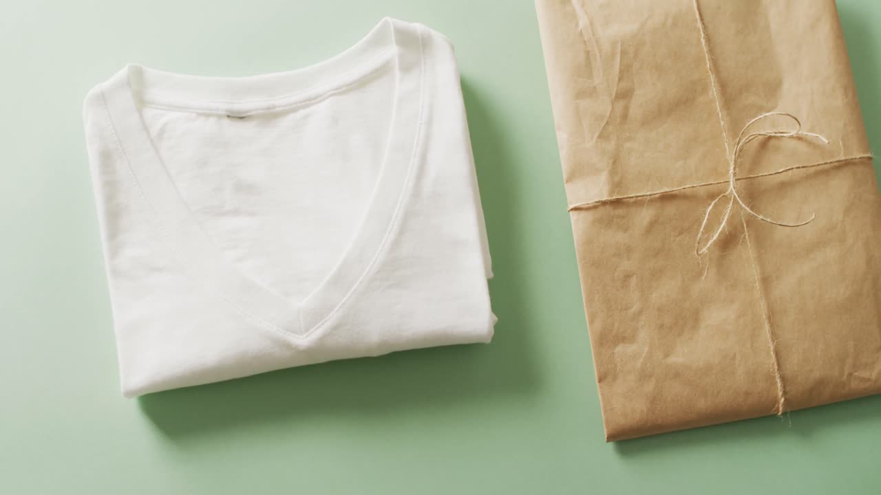 녹색 배경에 갈색 종이 패 ⁇ 과 함께  ⁇ 색 접힌 티셔츠의 클로즈업 비디오