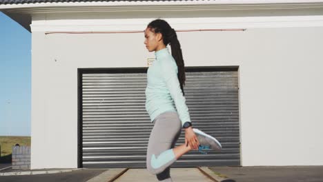 african american woman in sportswear stretching in street before exercising