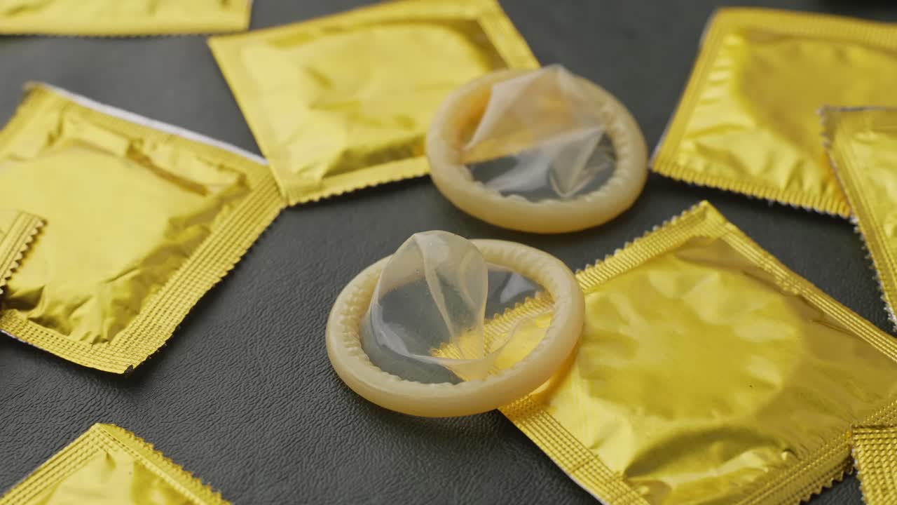Viser nærbillede af kondom holdt på fingrene