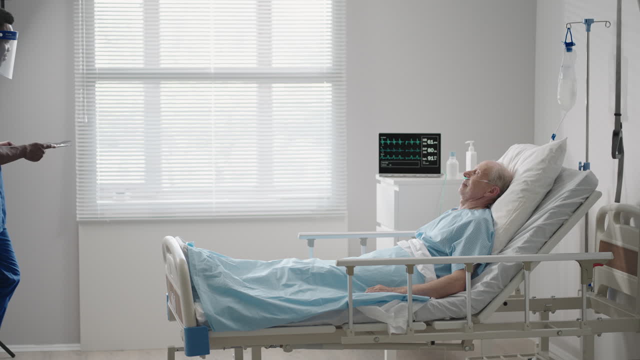 un médico negro con una máscara protectora entra y habla con pacientes con un anciano blanco acostado en una cama de hospital