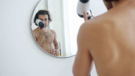 man drying his hair in front of a mirror