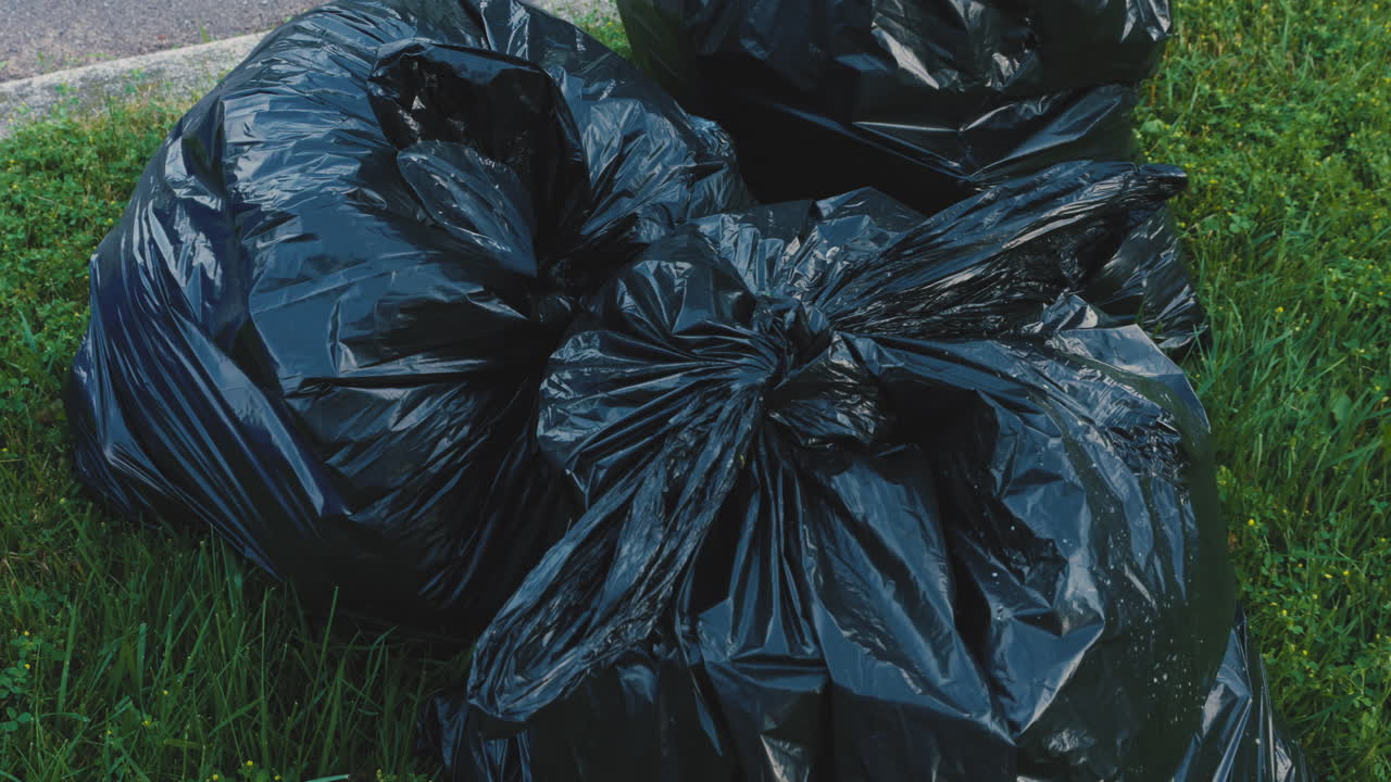 수거를 위해 연석에 놓인 검은색 플라스틱 쓰레기 봉투 더미