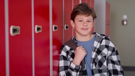 Video-portrait-of-smiling-teenager-standing-in-corridor-near-lockers.