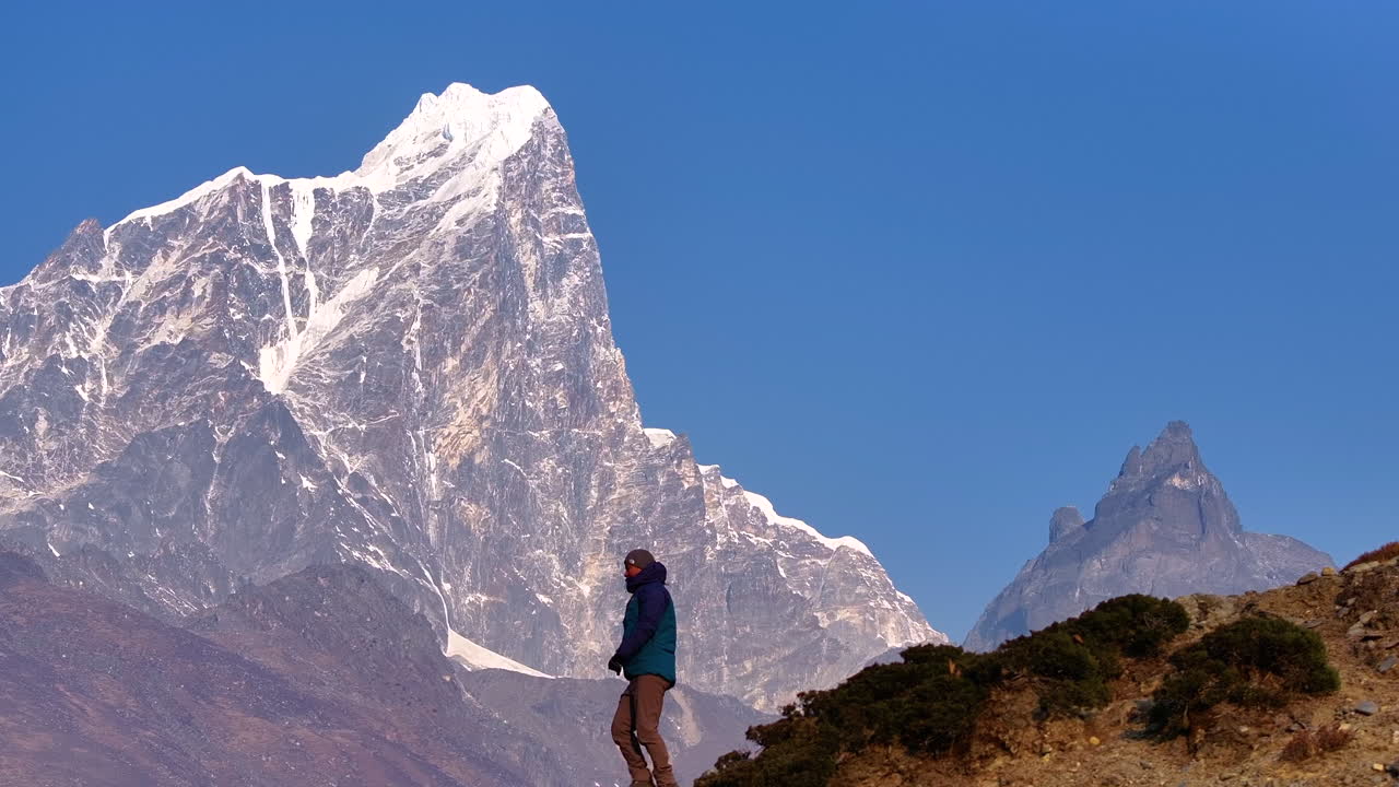 Aerial view of a tourist climbing down trek in Dingboche, Khumbu region. Mt. Cholatse shines under sunlight, holy and spiritual Himalayan scene on Everest Base Camp trek, landscape of Nepal