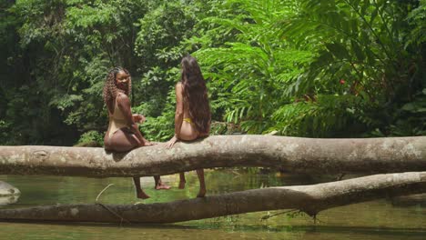 enjoying a tropical waterfall and having fun eating pineapple are two girls in bikinis in the caribbean.