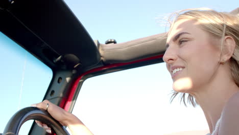 una mujer rubia caucásica conduciendo, la luz del sol iluminando su rostro alegre
