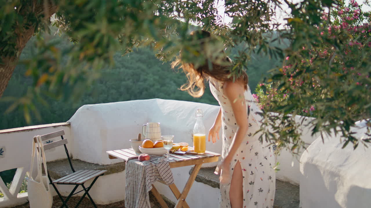 Ragazza delicata seduta al tavolo su un balcone con vista sulla natura e sulle montagne. Donna con i capelli al vento.