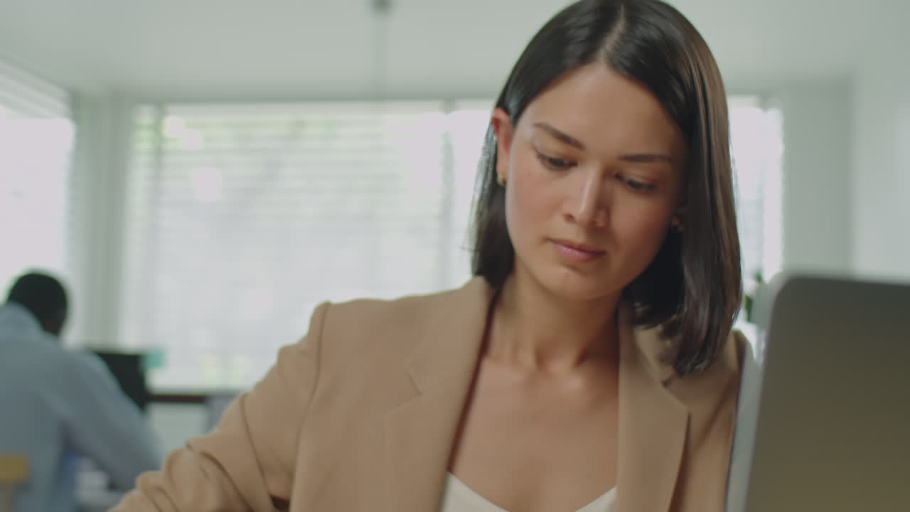 Businesswoman Using Laptop and Making Notes at Workplace