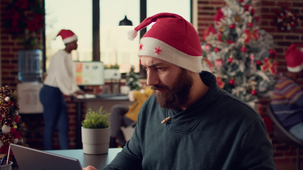 Man with santa hat using laptop in startup office