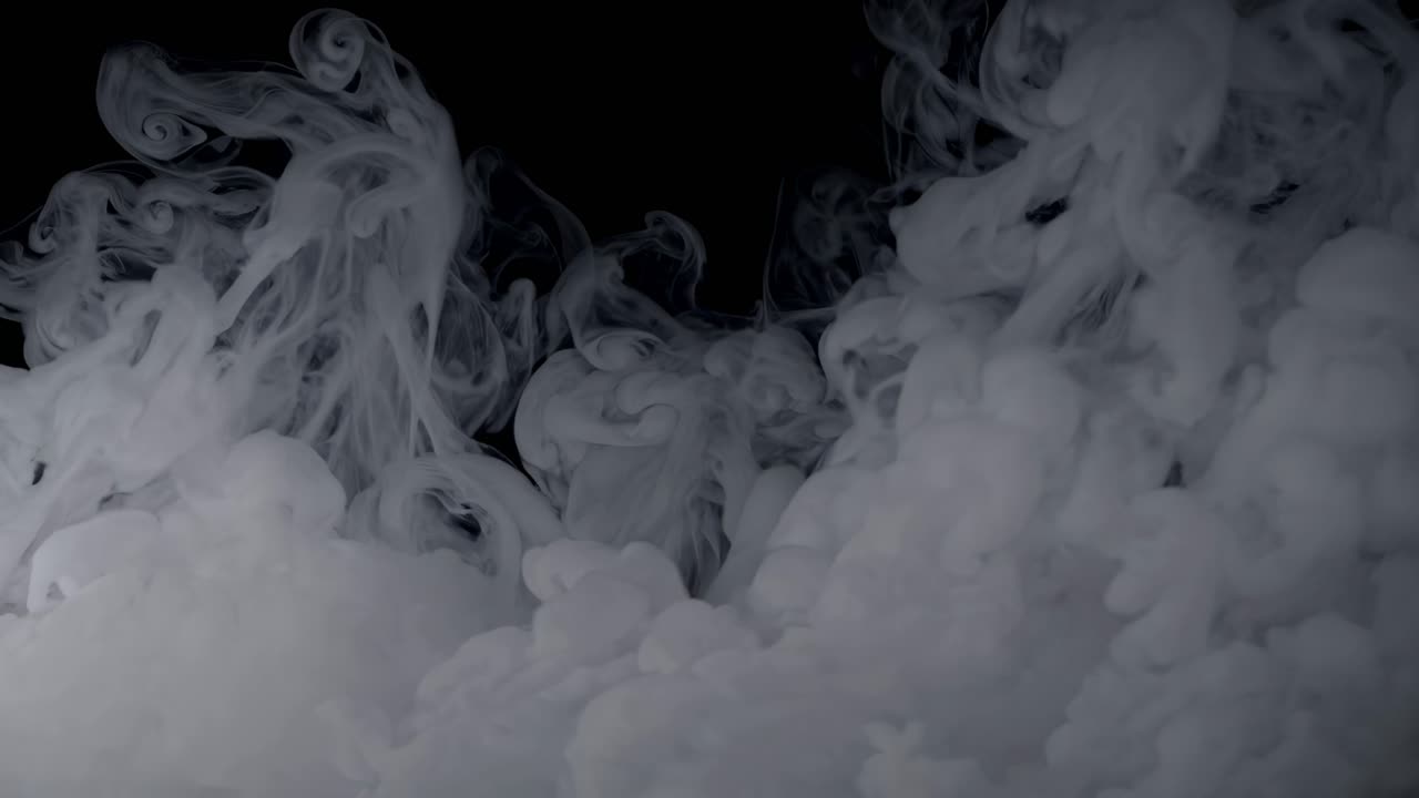 Un video ipnotico di fumo bianco turbinante su uno sfondo nero, ripreso da un angolo basso.