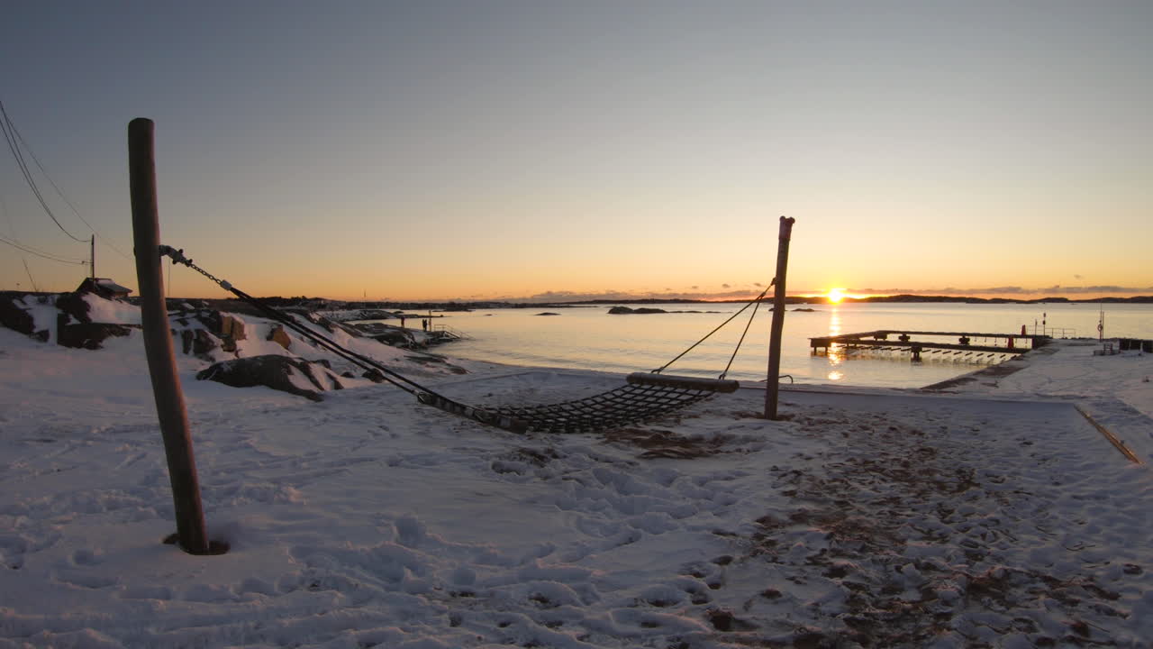 4k крупный план деревянного гамака на заснеженном пляже в зимний день во время заката в швеции
