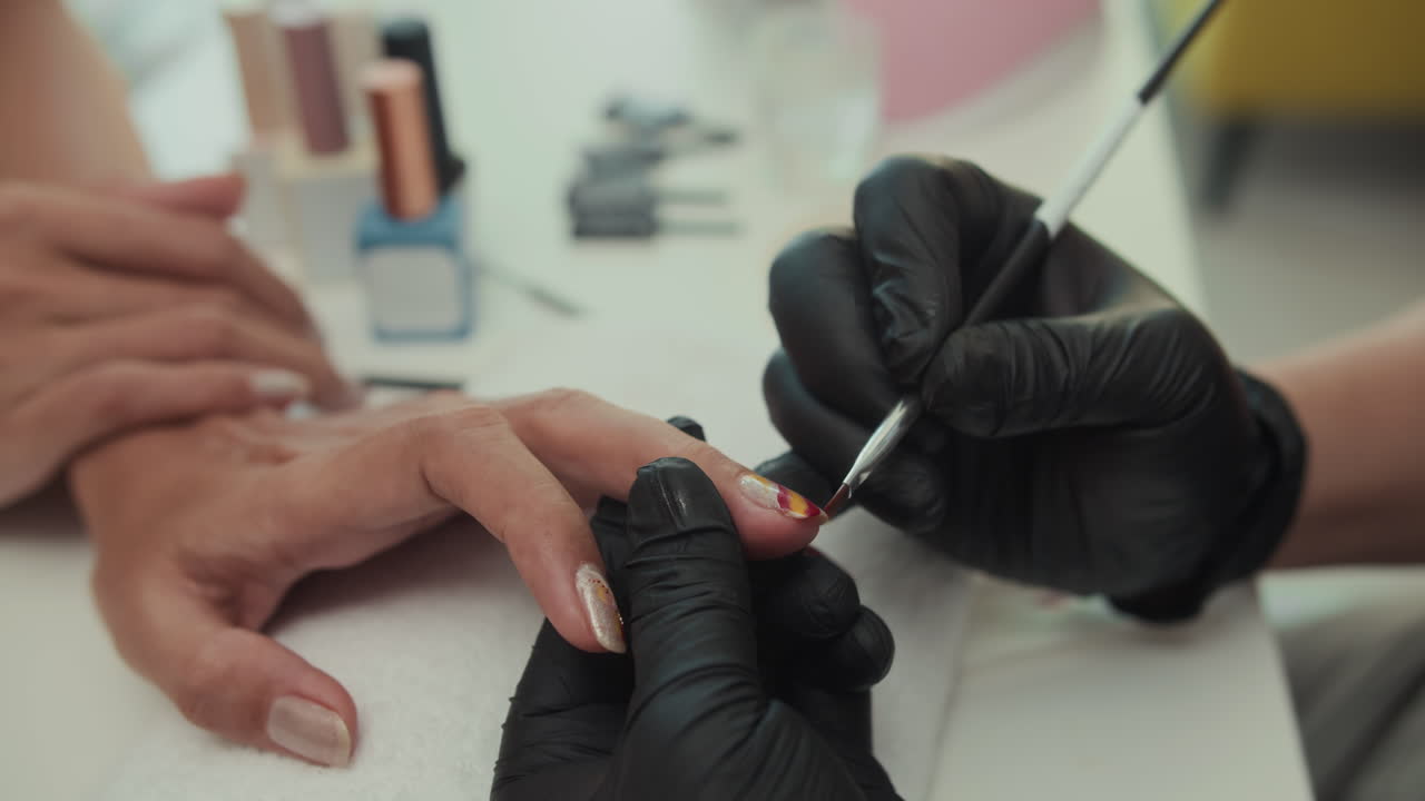 Manicurist Drawing on Female Nails with Brush in Salon