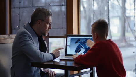 father and son working on a design project in a cafe