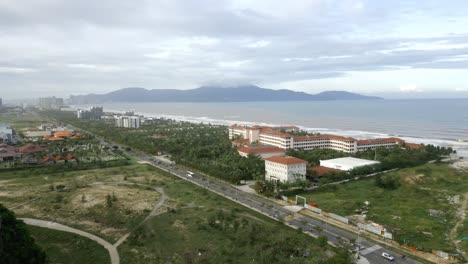 flyover from the mountains to ha my beach on a cloudy day with wave hitting the shore in da nang, vietnam