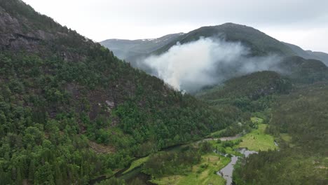 Aerial-approaching-wildfire-and-smoke-in-remote-wilderness-valley---Dry-green-forest-after-long-heat-period