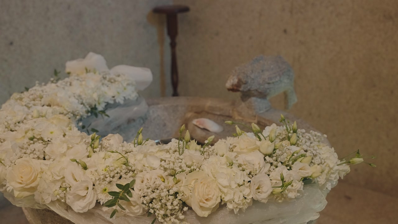baptism font decorated with white roses and flowers for catholic ceremony