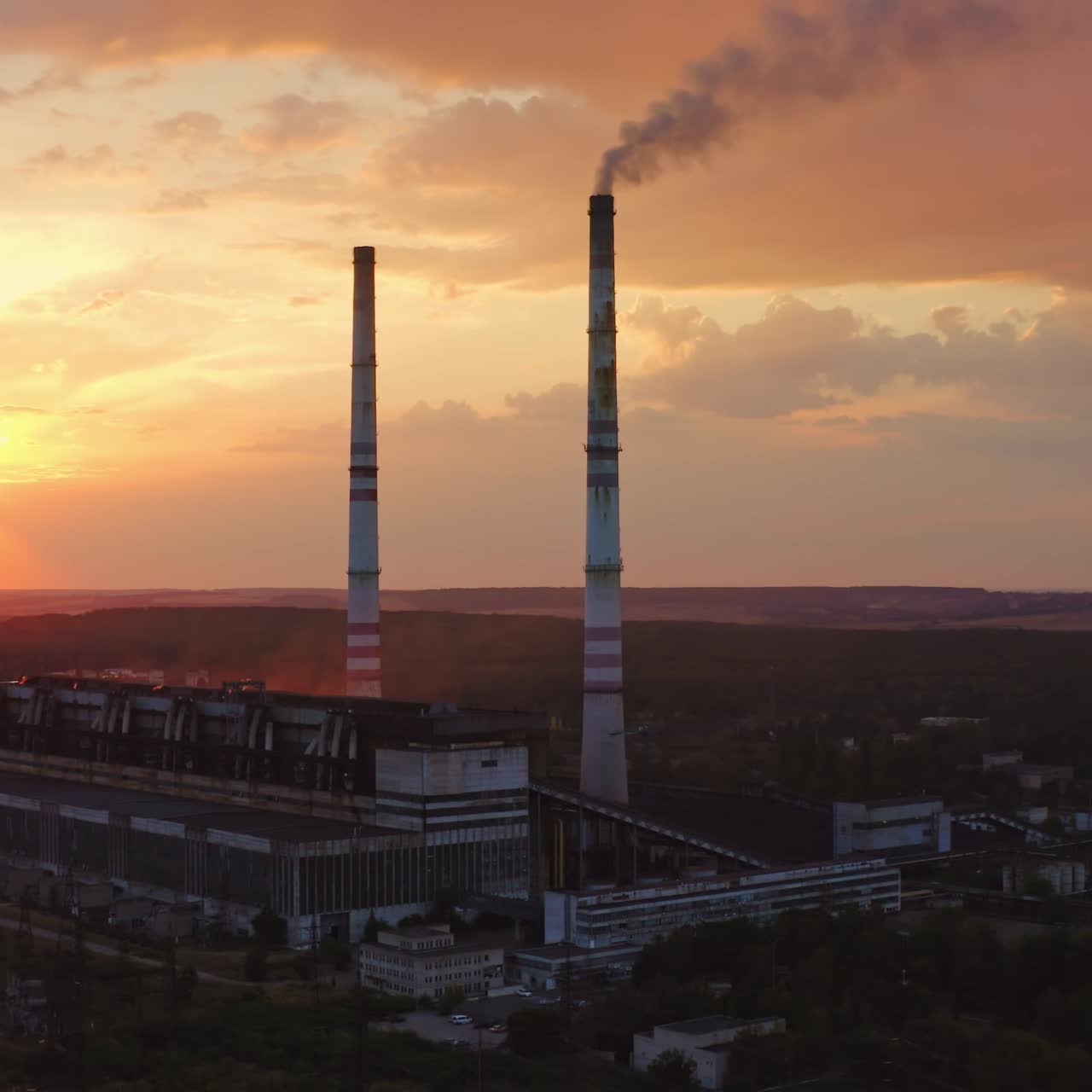 Chemical plant in nature. Dirty smoke goes from factory at sunset. Industrial pipe with harmful emissions pollute the environment. Aerial view.