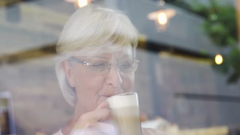 mujer mayor tomando un batido en el café 4k