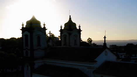 Aerial-view-of-Nosso-Senhor-do-Bonfim-church-back-side,-the-neighbourhood-and-the-ocean-at-background,-at-sunset,-Salvador,-Bahia,-Brazil