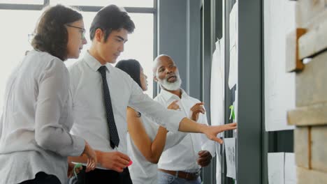 Executive-discussing-over-document-on-glass-wall-4k