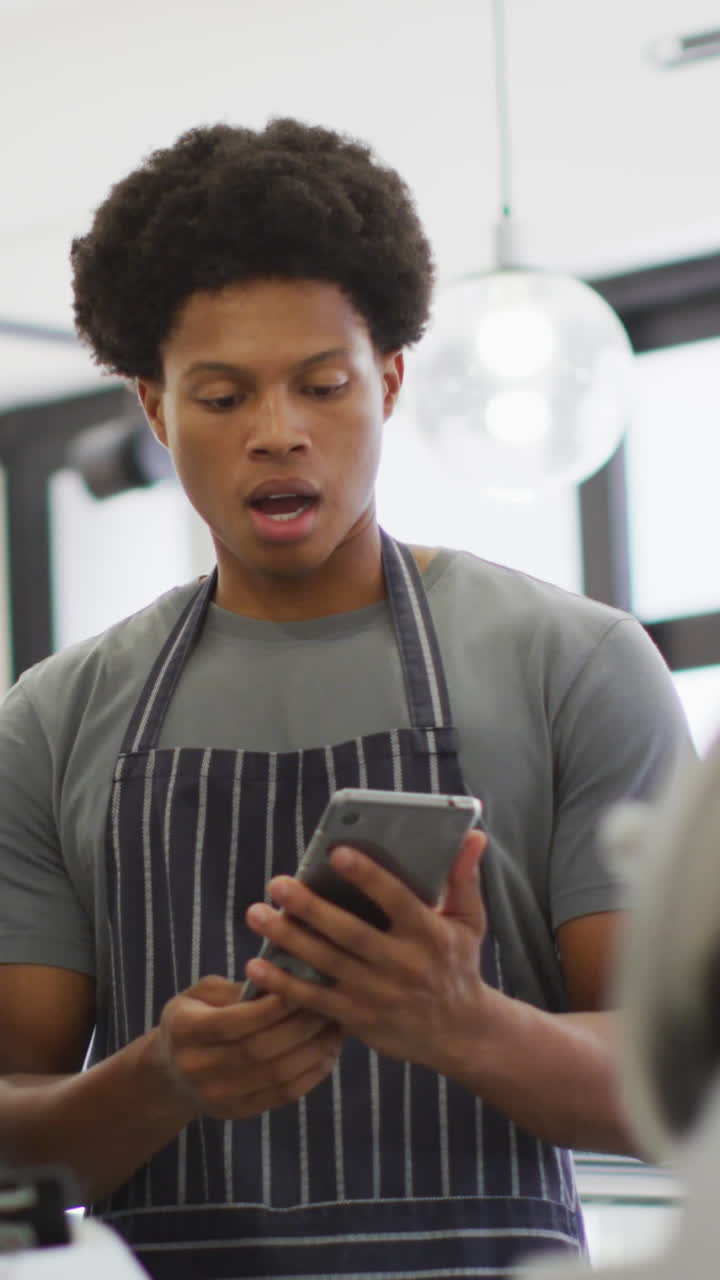 Animation of serious diverse female and male waiters using tablet at coffee shop and talking