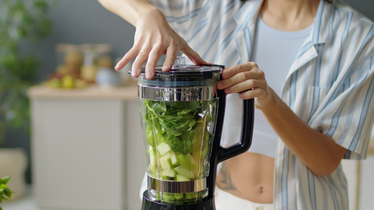 Woman Putting Fresh Ingredients for Green Smoothie into Blender