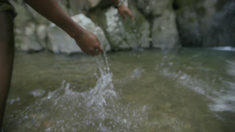 Imágenes-En-Cámara-Lenta-Siguiendo-Las-Manos-De-Un-Joven-Afroamericano-Mientras-Atraviesan-El-Agua-De-Un-Arroyo