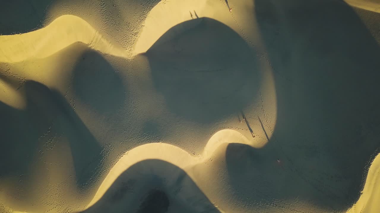 Aerial View of People Walking on Sand Dunes at Golden Hour