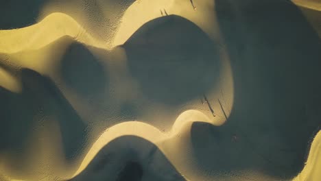 aerial view of people walking on sand dunes at golden hour