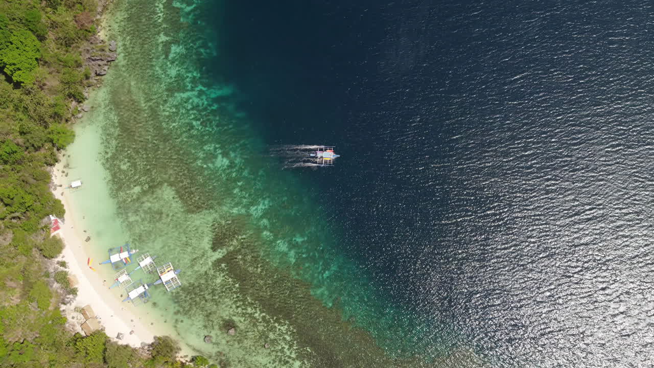 Remote beach at Palawan island, Philippines - Top-down aerial of turquoise water and traditional Bangka boat leaving shore