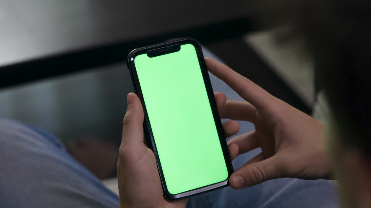 teléfono móvil en pantalla verde deslizar hacia arriba. mano adolescente masculino