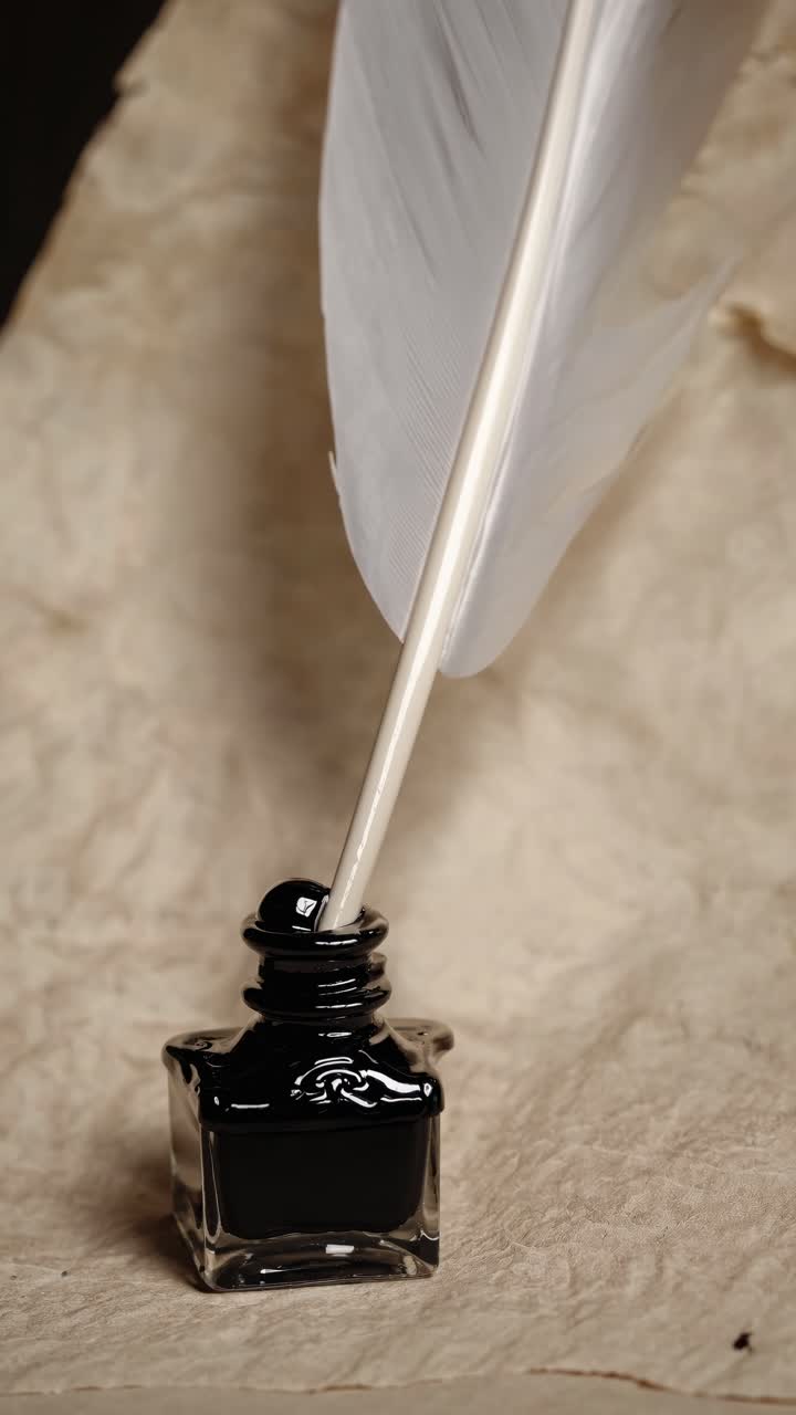 Close-up, vintage style video concept of a quill in an ink bottle on textured paper