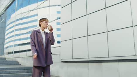 woman in a purple suit drinking coffee on stairs