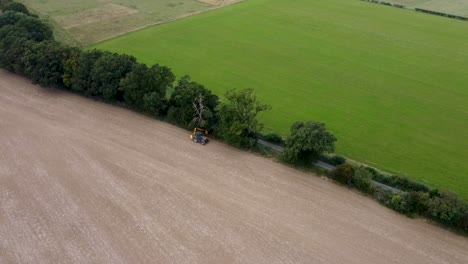 aerial view of hedge being trimmed by tractor in field