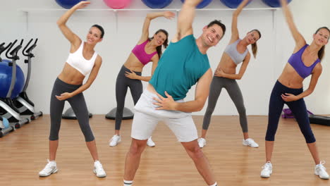 aerobics class stretching together led by instructor