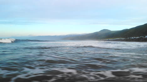 aerial drone flying fast and low over the water surface of the pacific ocean waves in ventura california at sunrise