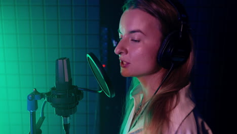 mujer cantando en el micrófono en el estudio de grabación