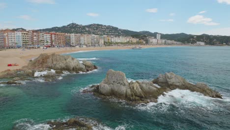 view of the main beach of lloret de mar with the buildings in the background and the transparent turquoise blue water of the beach recorded in 4k 10bit