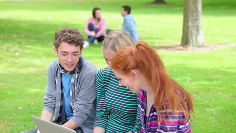 tres estudiantes mirando la computadora portátil juntos y riendo