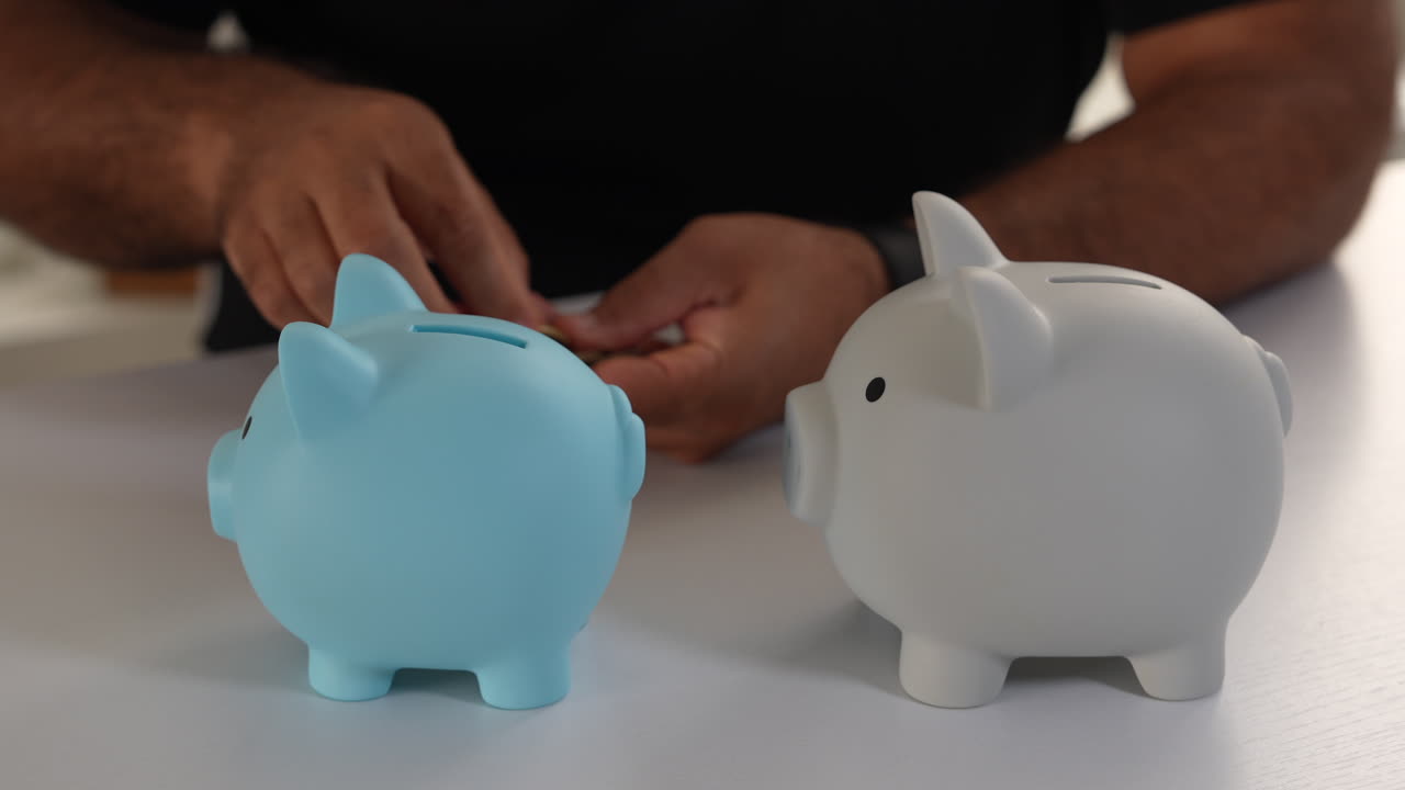 Detailed view of hands inserting coins into blue and white piggy banks. Soft lighting enhances the focus on saving money, evoking a sense of financial planning and responsibility