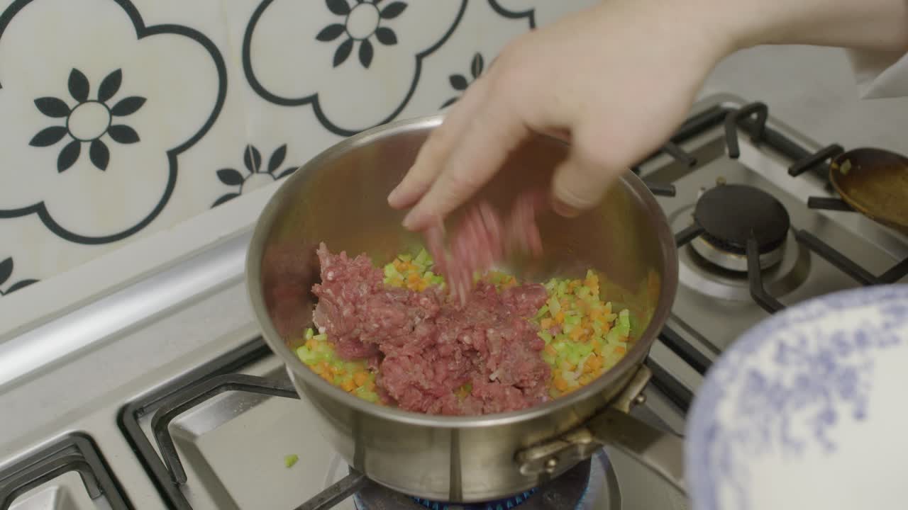 Adding minced meat into cooking pot with mixed vegetables