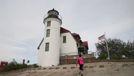 Mujer-Caminando-Cerca-Del-Histórico-Punto-Del-Faro-De-Betsie-En-Frankfort,-Michigan-A-Lo-Largo-Del-Lago-Michigan-Con-Video-Cardán-Desde-Atrás